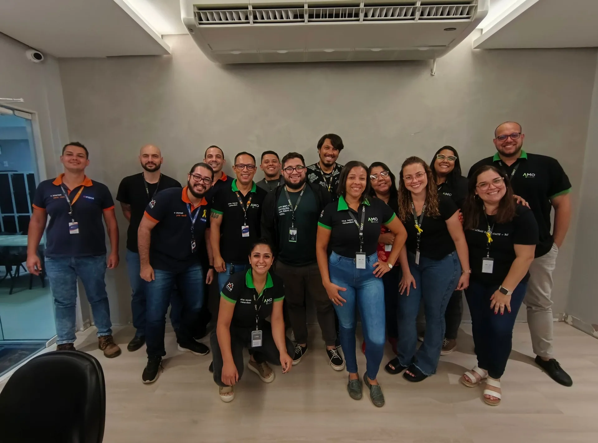 Turma de colaboradores reunida em sala, sorrindo para a foto